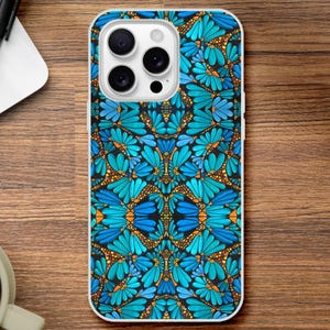 May include: A smartphone case featuring a repeating symmetrical pattern of bright blue flower petals and small orange dots against a dark background. The case has a cutout for a triple-lens camera system and a flash on the upper left corner.