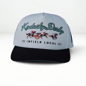 May include: A light blue and black baseball cap with the text "Kentucky Derby" in green script. The cap features an embroidered image of racehorses and the text "INFIELD LOCAL".