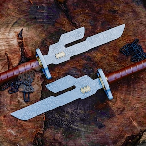 Op de afbeelding: Twee stalen dolken met bruin lederen handvatten en decoratieve metalen accenten worden gepresenteerd op een houten oppervlak. De bladen hebben een uniek, hoekig ontwerp. Een ketting en een logo zijn ook zichtbaar.