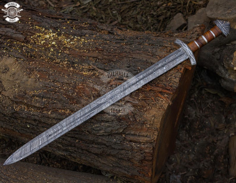 May include: A long, silver sword with a patterned blade and a wooden handle with metal accents. The sword is resting on a weathered, brown log. The image includes the text "Valhalla Legacy".