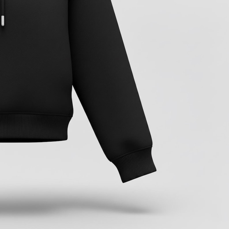 May include: A black hoodie with a ribbed hem and cuffs. The image shows a close-up of the sleeve and part of the body of the garment. The fabric appears to be a soft, medium-weight material.