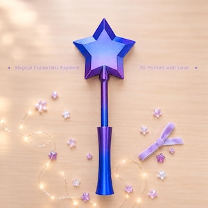 May include: A star-shaped wand featuring a gradient of blue and purple colors. The text Magical Contactless Payment and 3D Printed with Love is visible. The wand has a long, slender handle and a five-pointed star top with faceted edges.