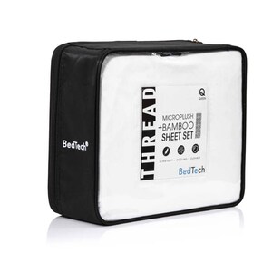 May include: A black zippered case containing a white sheet set. The case has a clear window displaying the sheets and a label that reads "THREAD MICROPLUSH + BAMBOO SHEET SET" with the BedTech logo. The sheet set is for a Queen size bed.