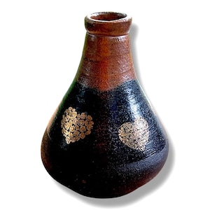 May include: A handmade ceramic vase with a dark brown and black color scheme. The vase features two gold heart-shaped designs. The vase has a rounded body and a narrow neck, and it is approximately 10 inches tall.