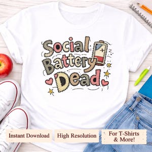 May include: White t-shirt featuring the phrase "Social Battery Dead" in a stitched design. The graphic includes a low battery icon, hearts, and stars. The shirt also has the text "Instant Download", "High Resolution", and "For T-Shirts & More!"