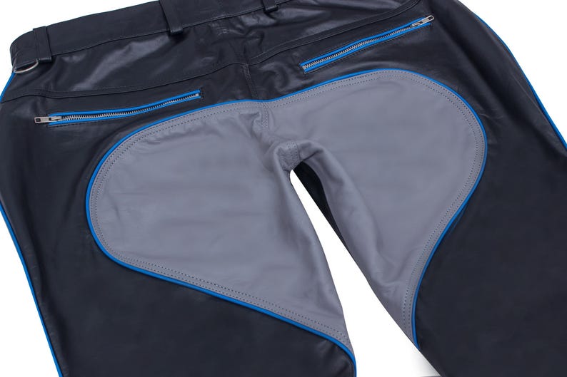 A close-up of the back of black leather pants, showing the gray heart-shaped seat panel with blue piping and belt loops.