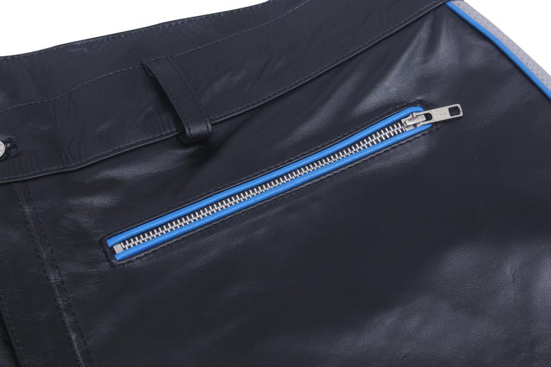 A close-up of the black leather pants, showing a diagonal pocket with a blue zipper.