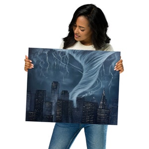 May include: A woman holds up a painting of a city skyline with a tornado in the background. The painting is dark blue and gray with white lightning bolts and a swirling white tornado.
