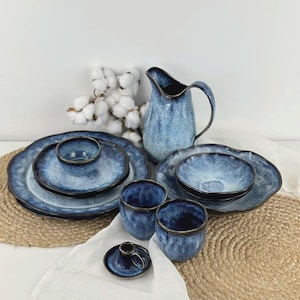 May include: A set of three ceramic mugs with a speckled, matte finish in cream, light grey, and dark grey. Each mug has a simple, modern design and a rounded handle.