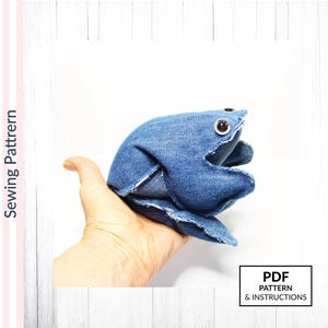 May include: A handmade denim frog toy with large, round eyes. The frog is crafted from blue denim fabric and has an open mouth. The image includes the text "PDF PATTERN & INSTRUCTIONS". The image also includes the text "Sewing Pattern".