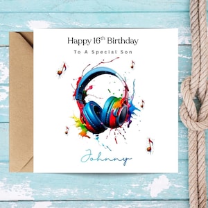 May include: A birthday card with a watercolour design. The card features a pair of blue headphones with rainbow accents and musical notes. Text reads "Happy 16th Birthday To A Special Son" and "Johnny". The card is paired with a brown envelope.