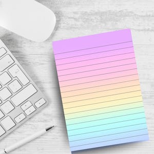 May include: A lined notepad with a pastel rainbow gradient, featuring shades of pink, yellow, and blue. A white keyboard, mouse, and pen are in the background, suggesting a workspace or office setting. The notepad is designed for writing notes.