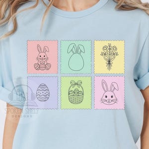 Peut inclure: T-shirt bleu clair avec six motifs de timbres-poste illustrant Pâques. Les motifs comprennent un lapin avec un œuf, des oreilles de lapin, un bouquet de fleurs, un œuf de Pâques, un panier avec un nœud et un visage de lapin. Le texte "Spoken Shelf Designs" est visible.
