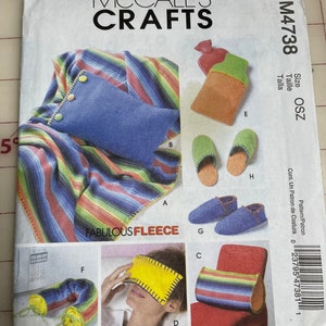 May include: A McCall's Crafts M4738 sewing pattern envelope titled Fabulous Fleece. The cover displays illustrations of fleece projects including a blue pillow, a hot water bottle cover, green and blue slippers, a yellow eye mask, and a neck wrap.
