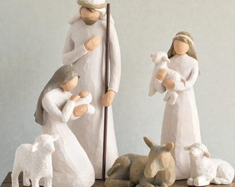 Könnte beinhalten: Eine Krippenszene mit geschnitzten Figuren von Maria, Josef und dem Jesuskind, sowie einer Schäferin mit einem Lamm, einem Esel und zwei Lämmern. Die Figuren sind hauptsächlich weiß mit braunen Akzenten, auf einer Holzoberfläche.