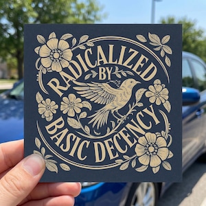 May include: Square sticker with a navy blue background and gold-colored floral and bird design. The text "RADICALIZED BY BASIC DECENCY" is arched around the bird illustration.