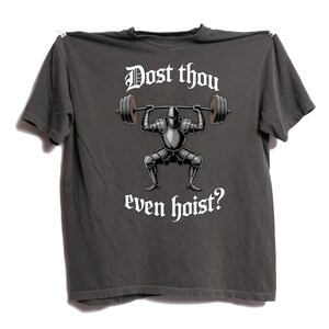 May include: Dark gray t-shirt with a graphic of a knight lifting a barbell. The text "Dost thou even hoist?" is printed above and below the knight illustration in a gothic font.