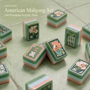 May include: A set of 160 premium acrylic American Mahjong tiles featuring green, white, and peach layers. The tiles display floral illustrations and traditional characters, including the number 6 and the text JadeTileStudio American Mahjong Set.