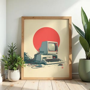 May include: A framed art print featuring a vintage beige computer with a monitor, keyboard, and mouse. A large red circle sits behind the computer, and tangled black cables extend from the back of the unit across the cream-colored background.