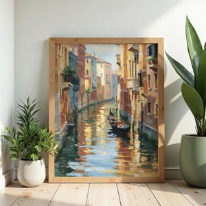 May include: A framed oil painting depicting a Venetian canal scene with a single gondola floating on the water. The artwork features warm-toned buildings in shades of yellow, orange, and brown, with reflections shimmering on the canal surface.
