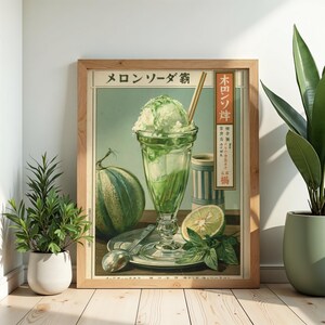 May include: A framed vintage-style poster featuring a green melon soda float in a glass, a whole melon, a lime slice, and mint leaves. The text reads "メロンソーダ" and "木田ソダ". The artwork is displayed in a light wood frame on a floor.
