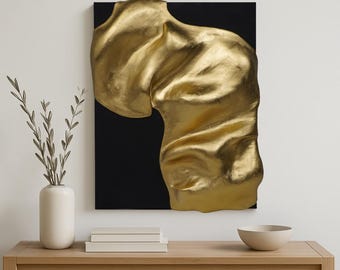 May include: A gold-coloured, abstract sculpture mounted on a black canvas. The sculpture has a textured, flowing form. The artwork is displayed on a light wood table, with a vase of greenery, books, and a bowl.