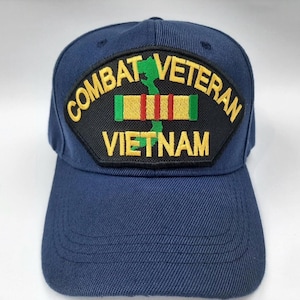 May include: Navy blue baseball cap with a patch that reads "COMBAT VETERAN VIETNAM". The patch features a green map of Vietnam and a ribbon with red and yellow stripes. The cap is made of a durable fabric.
