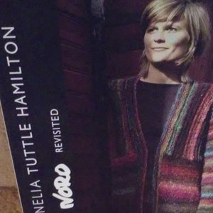 May include: A book cover featuring a woman wearing a colorful striped cardigan. The book title is "Cornelia Tuttle Hamilton" and the subtitle is "Noro Revisited".