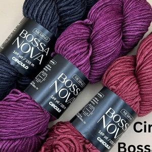 May include: Three skeins of Circulo Bossa Nova Merino yarn in black, purple, and burgundy. Each skein is labeled with the brand name and yarn weight.