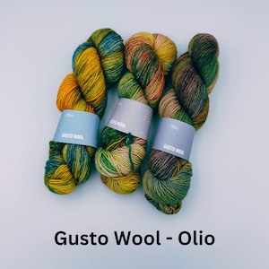 May include: Three skeins of yarn in shades of green, yellow, and brown. The yarn is labeled "Gusto Wool - Olio".