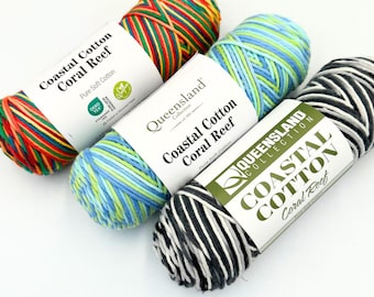 May include: Three skeins of Queensland Collection Coastal Cotton Coral Reef yarn. One skein features red, yellow, and green stripes, one has light blue and green tones, and the third is black and white. Each has a white paper label.