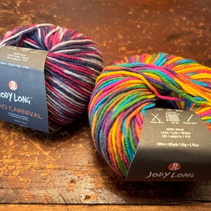 May include: Two balls of yarn in different color combinations. The yarn is labeled "JODY LONG CIAO CARNIVAL" and is 100% wool. The label also states that the yarn is 105m/115yds/150g/176oz.