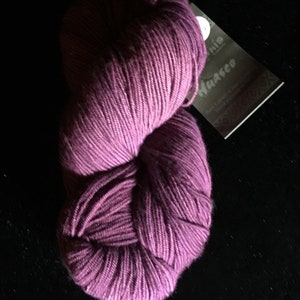 May include: A skein of purple yarn with a white label that says "Muga Silk" and "Handspun".