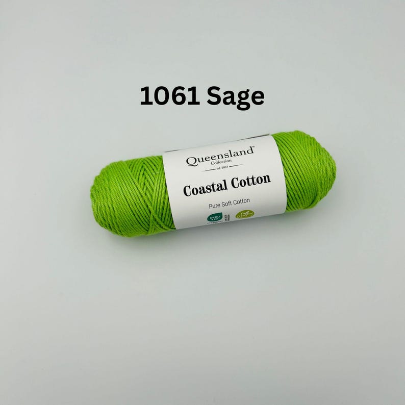 K&ouml;nnte beinhalten: Eine Garnrolle in Gr&uuml;n mit der Aufschrift "Queensland Collection Coastal Cotton Pure Soft Cotton" und dem Farbcode 1061 Sage.