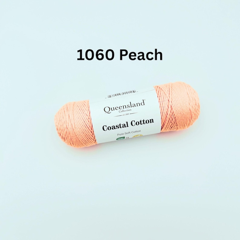 K&ouml;nnte beinhalten: Ein Kn&auml;uel peachfarbenes Garn mit der Aufschrift "Queensland Collection Coastal Cotton Pure Soft Cotton" und dem Farbcode 1060 Peach.
