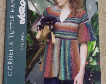May include: A book cover featuring a woman wearing a colourful striped sweater and holding a small black and brown puppy. The book title is "Eternal" and the author is "Cornelia Tuttle Hamilton".