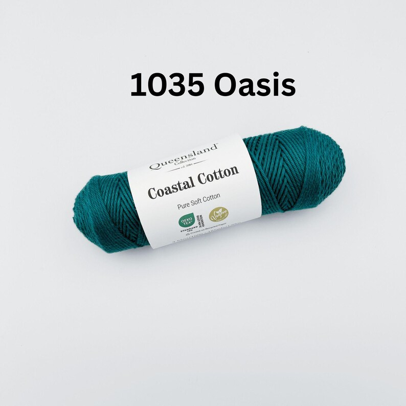 K&ouml;nnte beinhalten: Eine Garnrolle in blaugr&uuml;ner Farbe mit der Aufschrift "Queensland Collection Coastal Cotton Pure Soft Cotton". Das Etikett enth&auml;lt auch die Nummer 1035 und das Wort "Oasis".