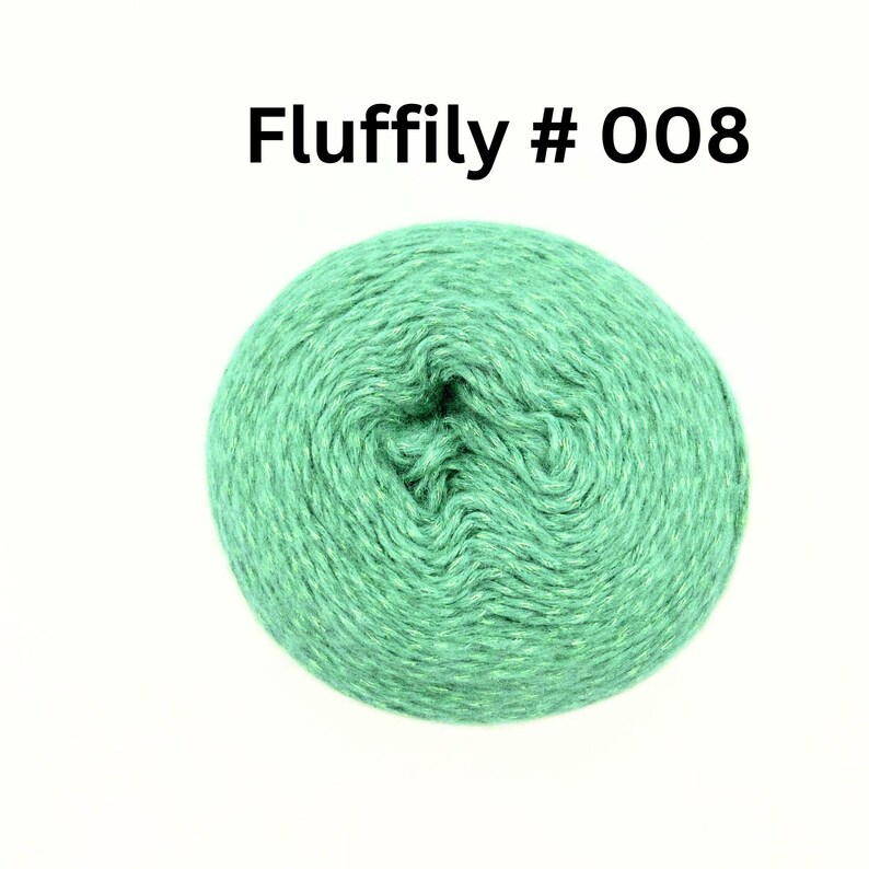 May include: A ball of green yarn with the text "Fluffily # 008" in black. The yarn is a light green colour and appears to be soft and fluffy. The yarn is tightly wound into a ball shape.