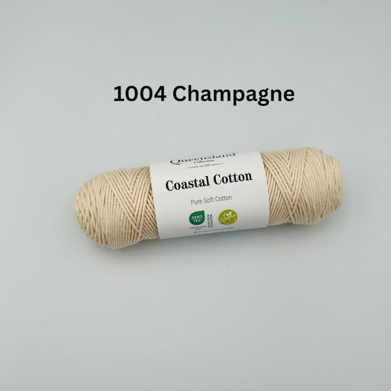 K&ouml;nnte beinhalten: Ein Kn&auml;uel beigefarbenes Coastal Cotton Garn von Queensland Cotton, mit der Bezeichnung "1004 Champagne". Das Garn ist 100% Baumwolle und tr&auml;gt das Oeko-Tex- und GOTS-Siegel.