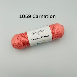 K&ouml;nnte beinhalten: Eine Spule korallenrosa Garn mit der Aufschrift "Queensland Collection Coastal Cotton Pure Soft Cotton" und dem Farbcode 1059 Carnation.