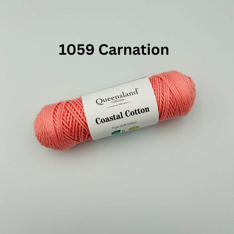K&ouml;nnte beinhalten: Eine Spule korallenrosa Garn mit der Aufschrift "Queensland Collection Coastal Cotton Pure Soft Cotton" und dem Farbcode 1059 Carnation.