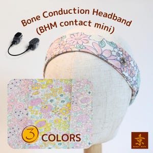 以下が含まれることがあります： 「Bone Conduction Headband (BHM contact mini)」の文字が入った、花柄の骨伝導ヘッドバンド。マネキンの頭に表示されています。画像には、ヘッドバンドの生地のクローズアップと「3 COLORS」の文字も表示されています。