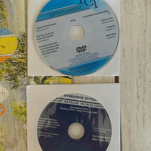 May include: Two DVDs in white paper sleeves. One DVD is labeled "PGT Entertainment" with "The SpongeBob SquarePants Movie" and other game titles. The other DVD is labeled "Operating System" and "Windows Vista Home Premium 32BIT".