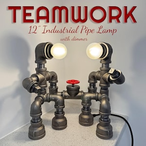 May include: A 12-inch industrial pipe lamp with dimmer, constructed from dark gray metal pipes and fittings. The lamp features two light bulbs and a red valve. The word "TEAMWORK" is displayed above the lamp.