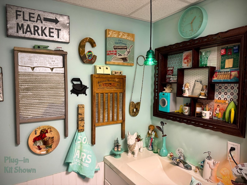 May include: A wall display featuring two vintage washboards, a metal Flea Market sign with an arrow, a letter C, a Fine Fabrics sign, a large safety pin, a wall-mounted shelf with various small items, a clock, and a light blue towel.