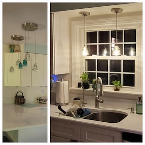 May include: A set of pendant lights featuring clear and teal glass insulators suspended from a circular brushed nickel ceiling canopy. The lights are arranged in a cluster, with some glass pieces illuminated to emit a warm, soft glow.