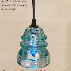 May include: A light blue glass insulator pendant light kit with a black cord. Text reads: Includes everything you need to turn your glass insulator into a hanging pendant light. Glass insulator and bulb not included. Hardwire version also requires a ceiling canopy kit, which is not included.