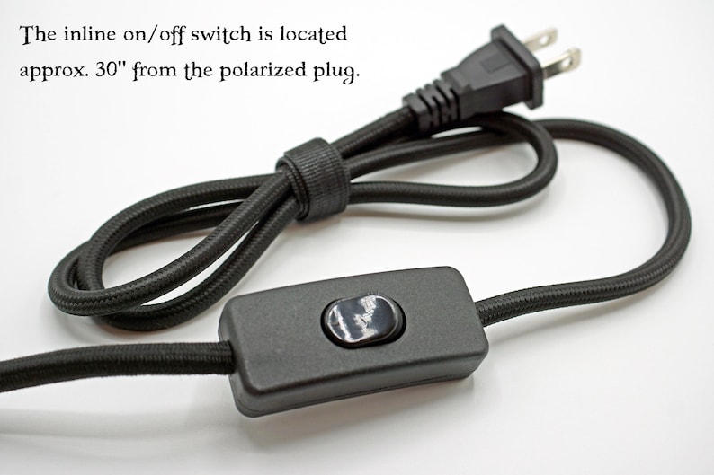 May include: A black fabric-covered electrical cord featuring a polarized plug and an inline on/off switch. The text states: The inline on/off switch is located approx. 30" from the polarized plug. The cord is coiled and secured with a black cable tie.