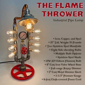 May include: An industrial pipe lamp titled The Flame Thrower, constructed from iron, copper, and steel. It features a 21-inch tall frame, a red 8-inch cast iron valve wheel base, a pressure gauge, and eight side-shooting bulbs with a stainless steel shade.