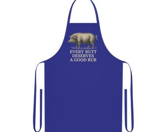 Op de afbeelding: Koningsblauwe schort met een afbeelding van een varken en de tekst "EVERY BUTT DESERVES A GOOD RUB". De schort heeft een nekband en strikbanden. Ideaal om te koken of te grillen.